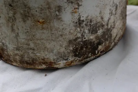 Ржавый нижний край белой эмалированной кастрюли