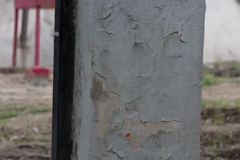 Отслаивающаяся серая краска на поверхности колонны
