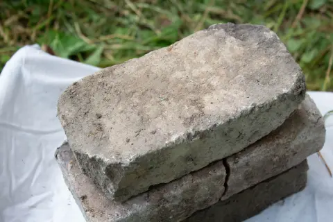 Старый серый кирпич с закруглённым потёртым торцом