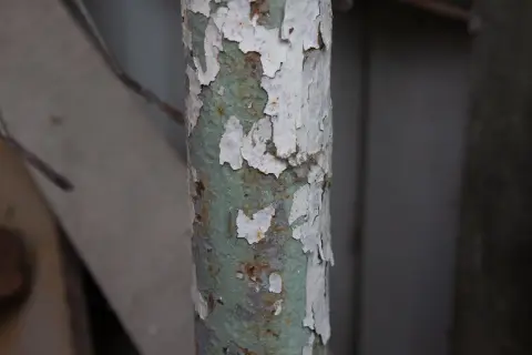 Обнажённый зелёный подслой на облупившейся трубе