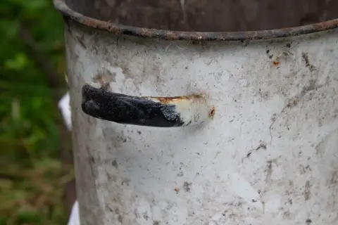 Чёрная ручка и ржавый край кастрюли