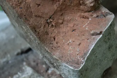 Сломанный край красного кирпича и серая кладка